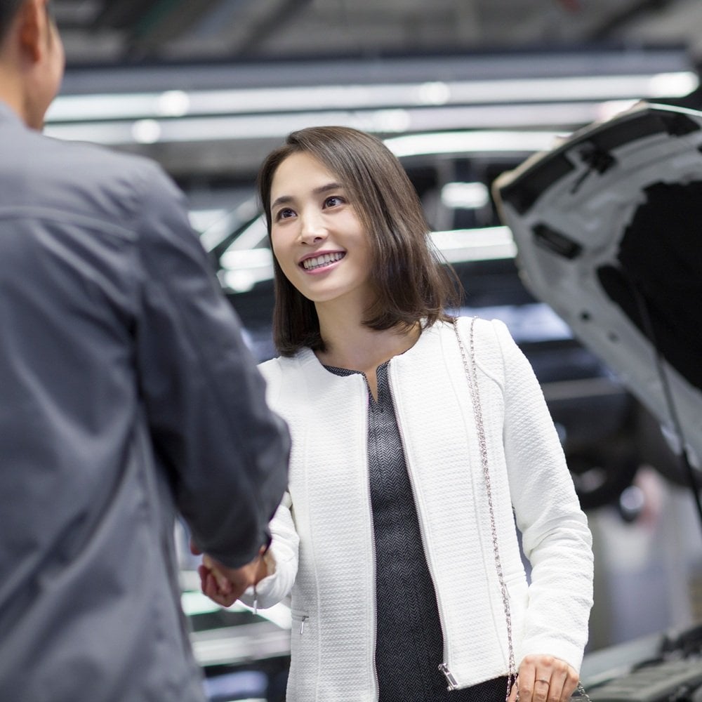 person shaking hands beside open car