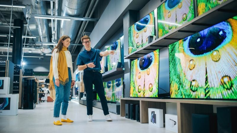 People shopping for televisions in electronics store