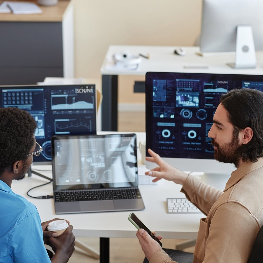 Two people analyzing data on computer screens.