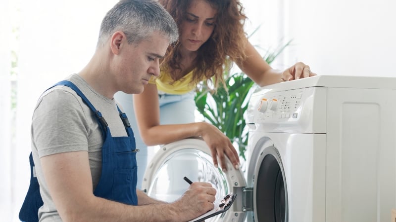 Technician inspecting washing machine at home