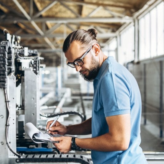 Man inspects machinery in manufacturing plant