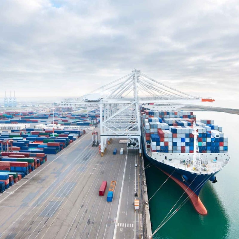 Container ship loading at a busy port terminal.