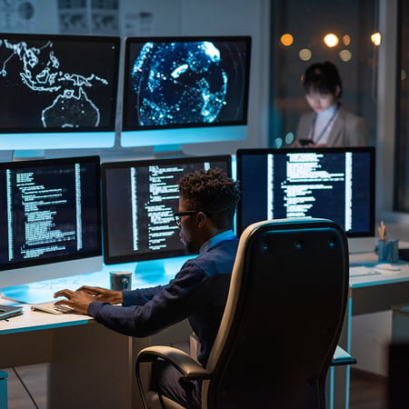 man sitting in front of mutiple monitors