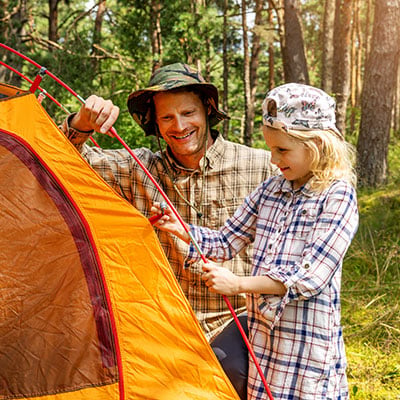 father and daughter setting up a tent