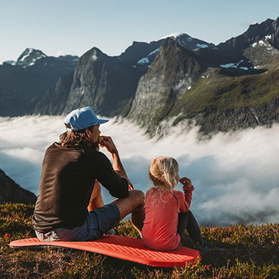 father and daughter sitting on top a mountain