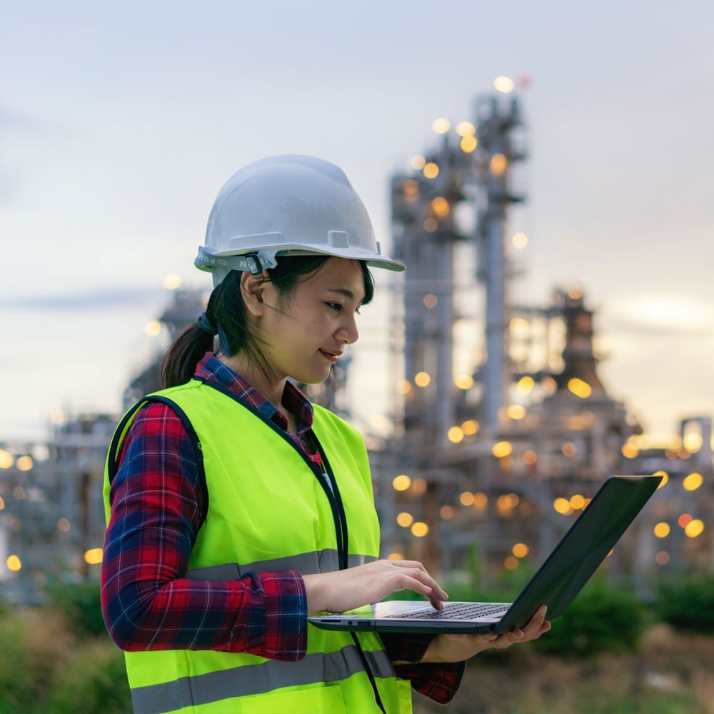 Engineer on PC in front of power plant