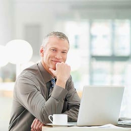 guys smiling at table with laptop