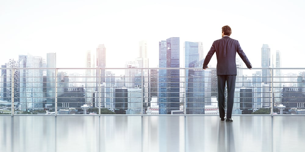 man standing on balcony looking at city