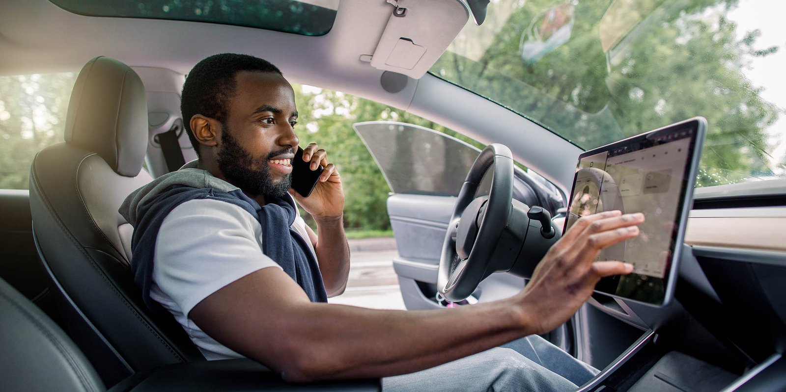 Mann sitz im Auto und hantiert mit Boardcomputer. Er überprüft die Kontrollleuchten