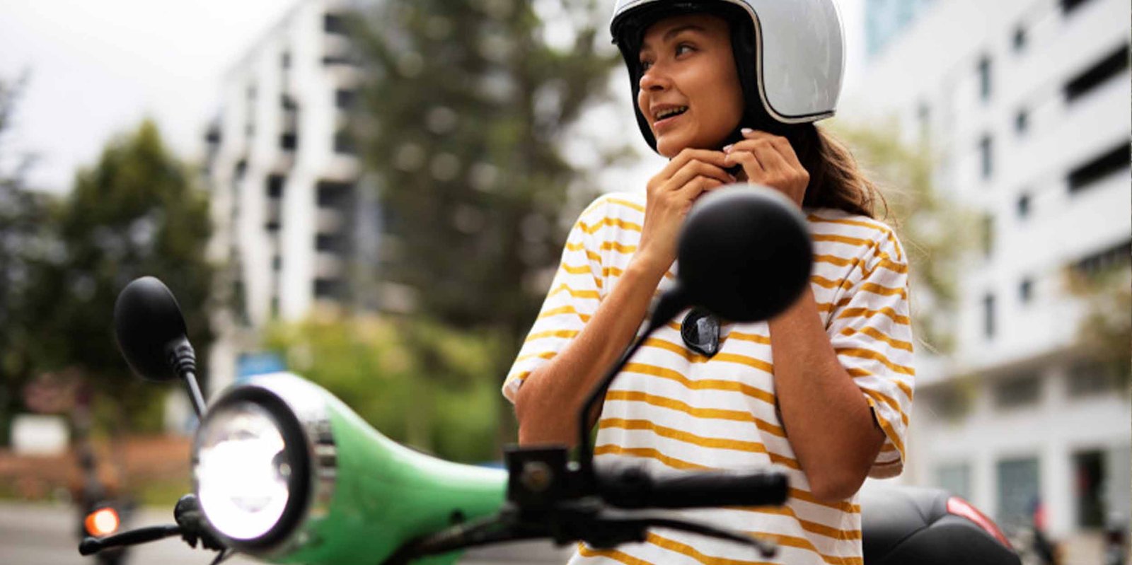 Frau sitzt am Moped (Roller) und setzt sich den Helm auf