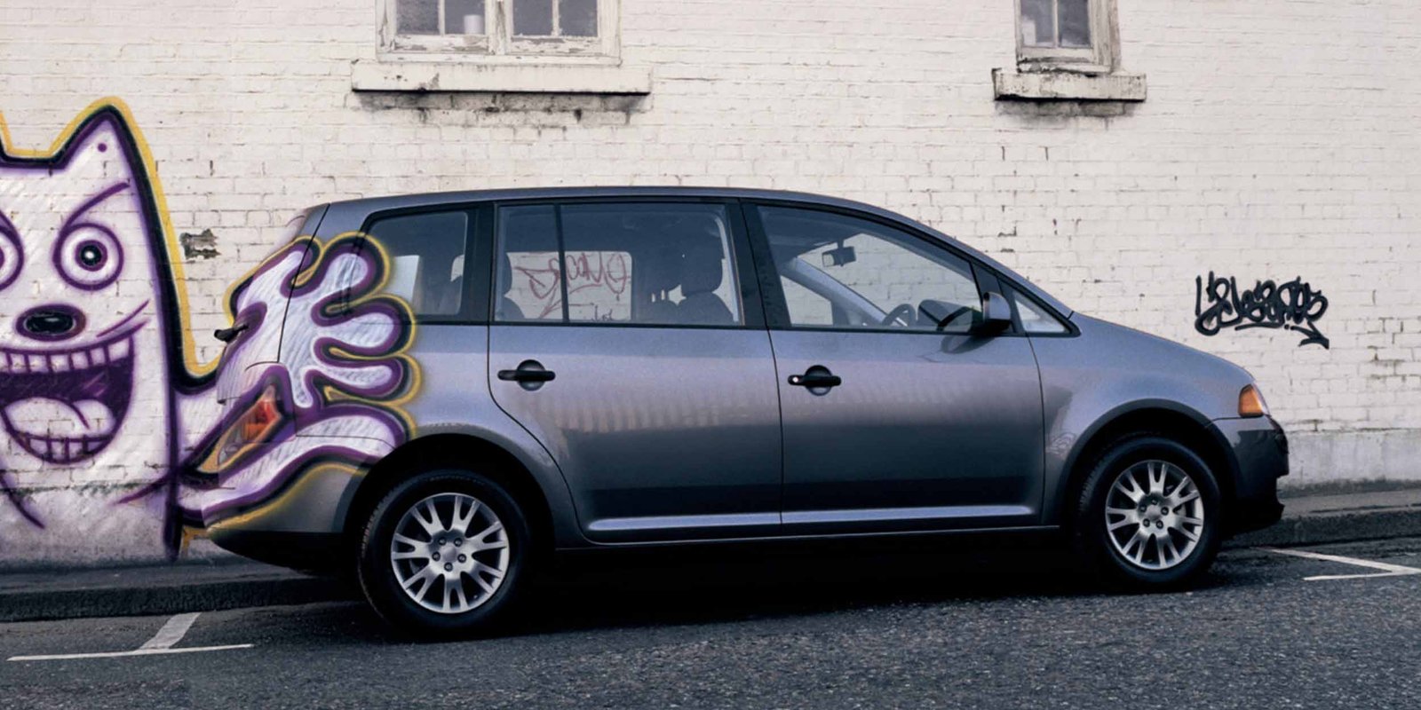 ein Graffitti wurde auf eine Hauswand und auf das davor geparkte  Auto gesprayed