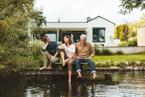 Drei Personen sitzen im Garten und stecken die Fuße in einen Teich | Zurich Connect Gartenversicherung