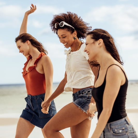 Frauen laufen lachend den Strand entlang