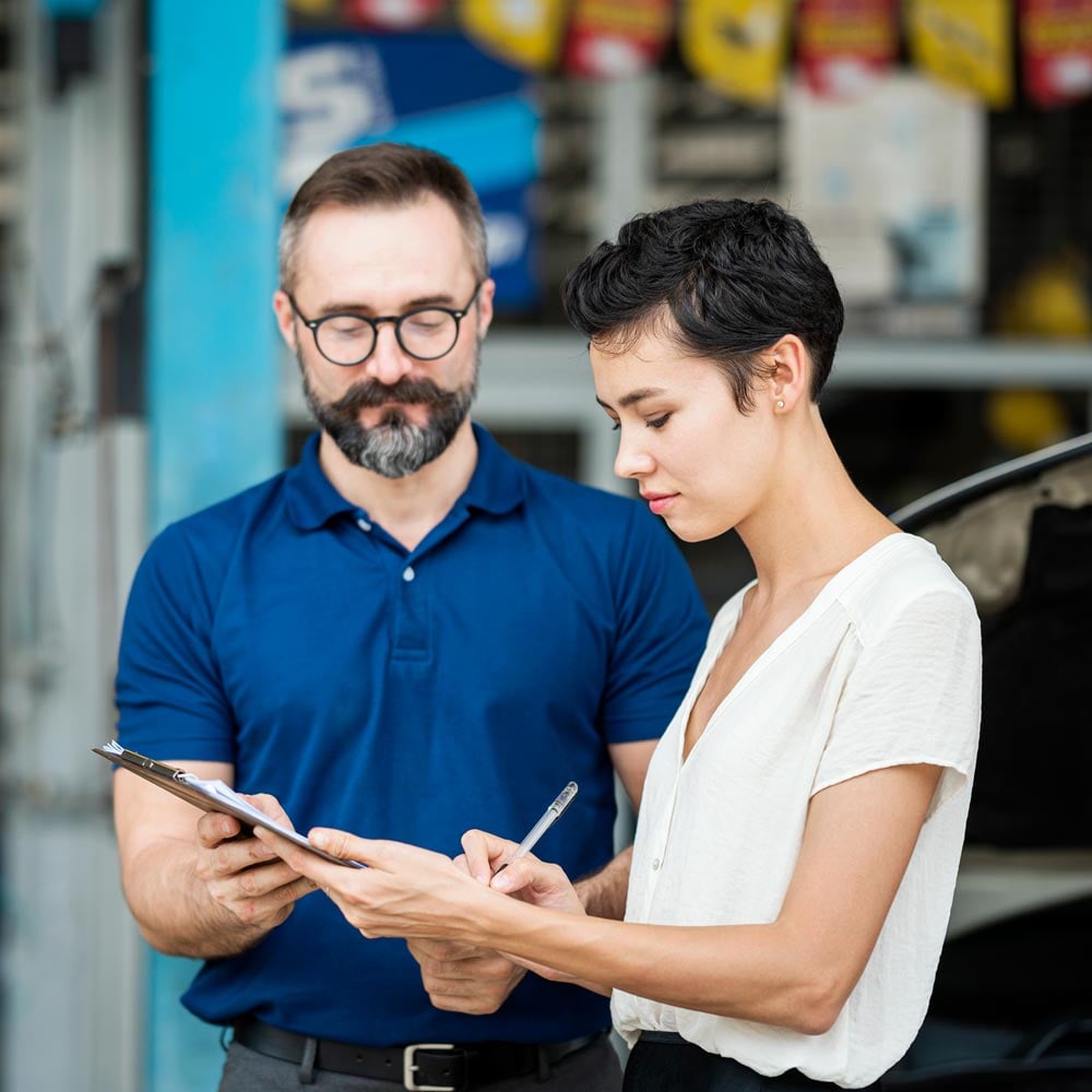 Female customer sign accept on car repair checklist or claim form with auto mechanic at Auto Repair Center