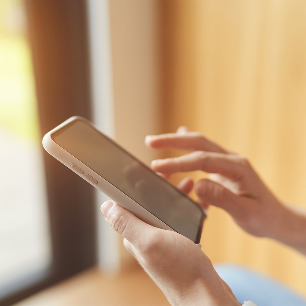 Person using a mobile phone by a window with natural light