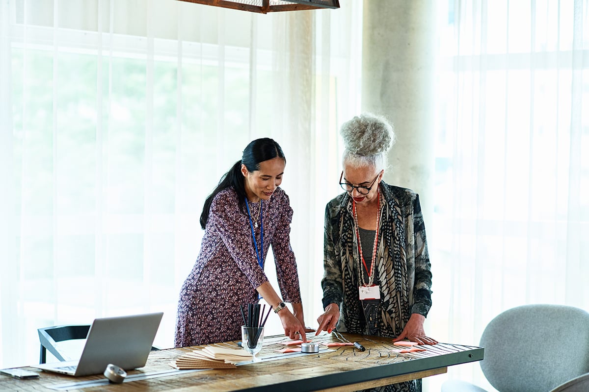Two female professionals in modern office discussing ideas and concepts, planning, looking at options
