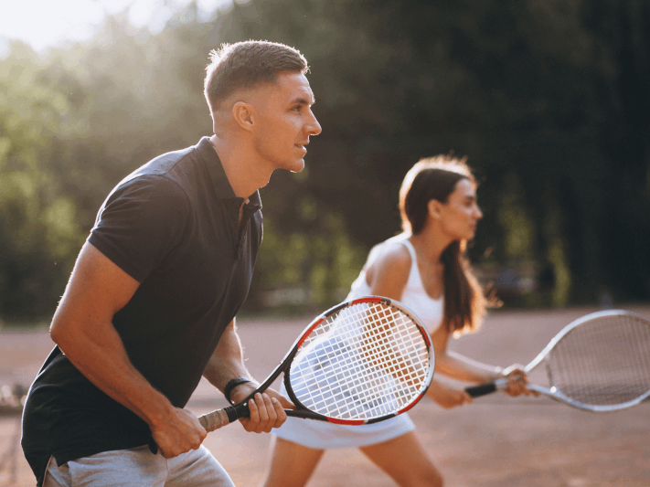 Two people playing tennis outdoors.