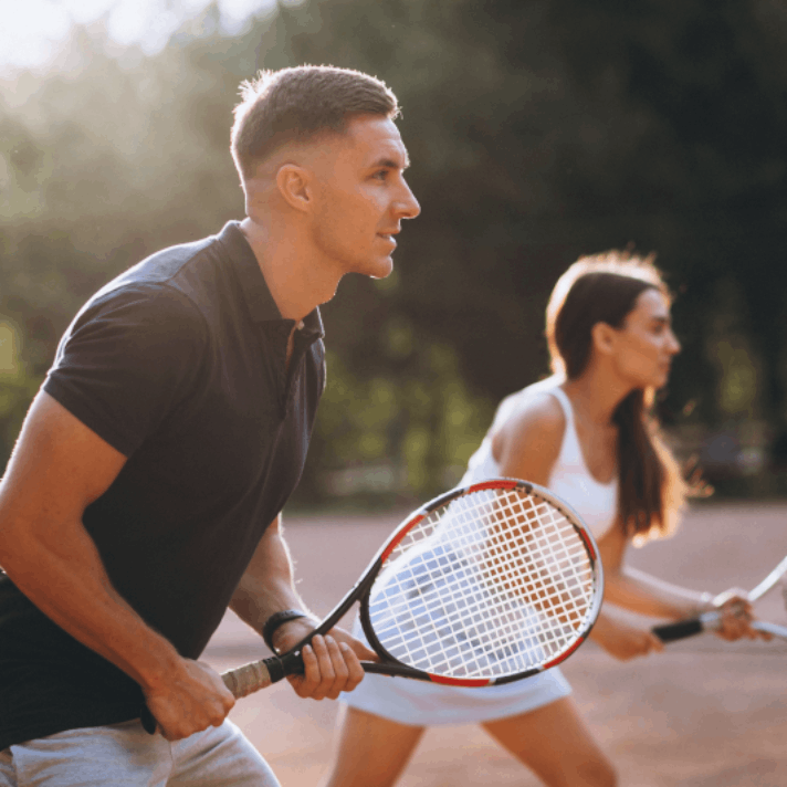 Two people playing tennis outdoors.