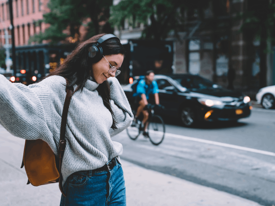 Young woman listening to music on city street.