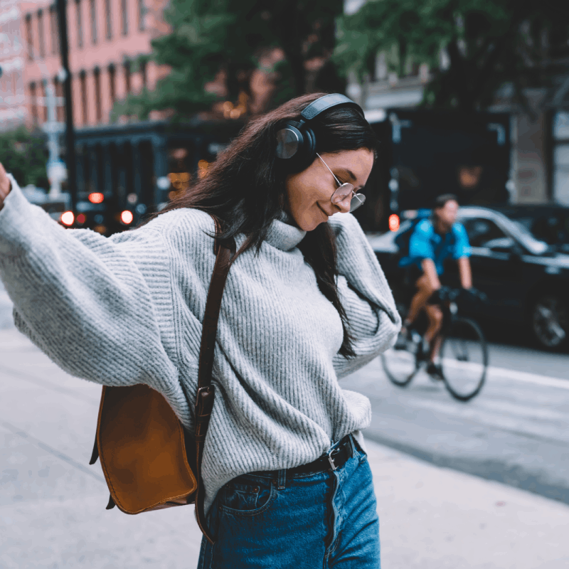 Young woman listening to music on city street.