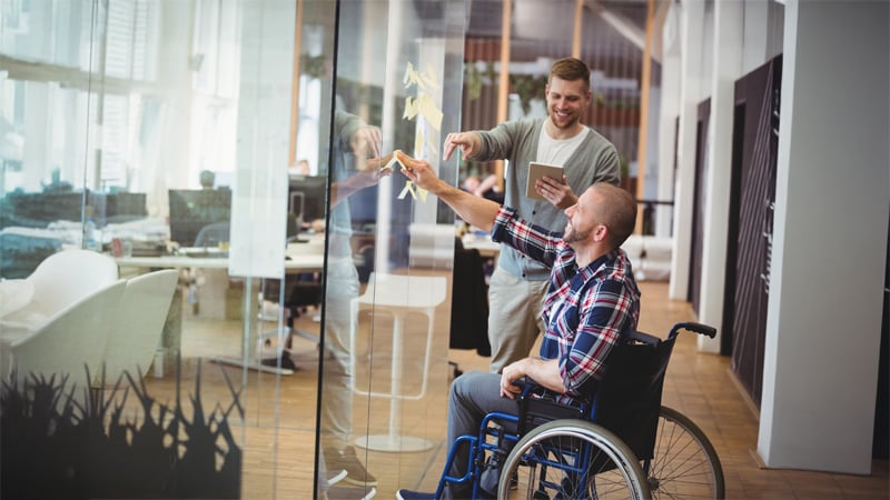 colleagues placing sticky notes on glass wall