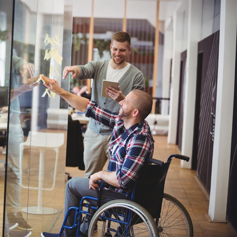 colleagues placing sticky notes on glass wall