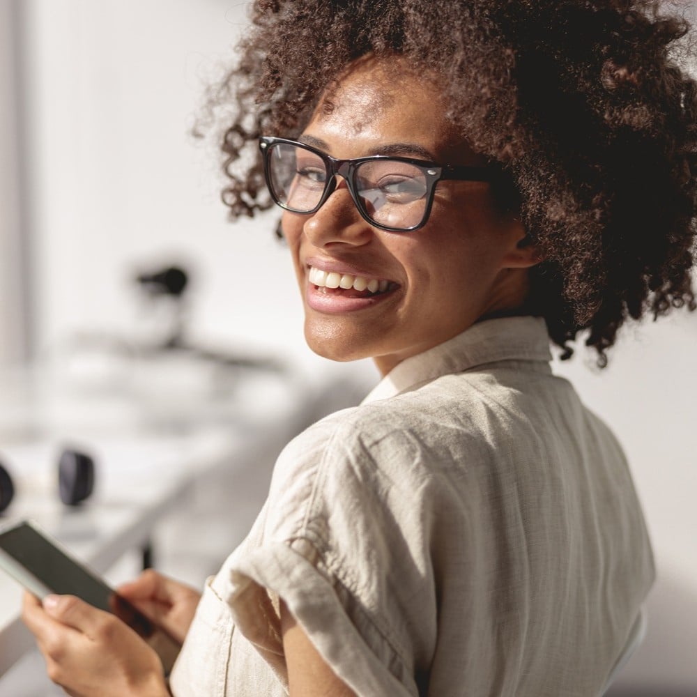 Femme souriante avec un téléphone mobile à la main