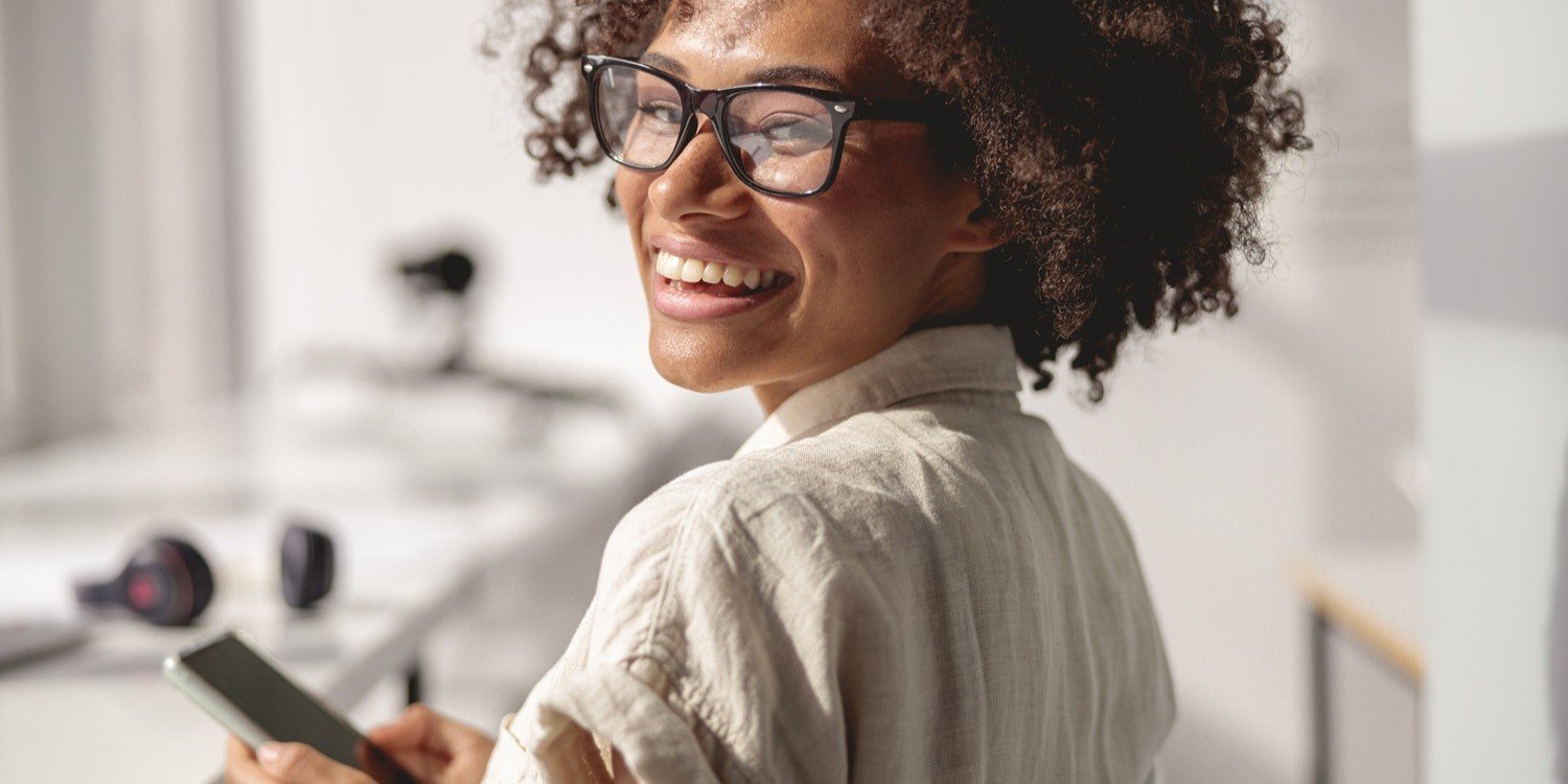 Femme souriante avec un téléphone mobile à la main