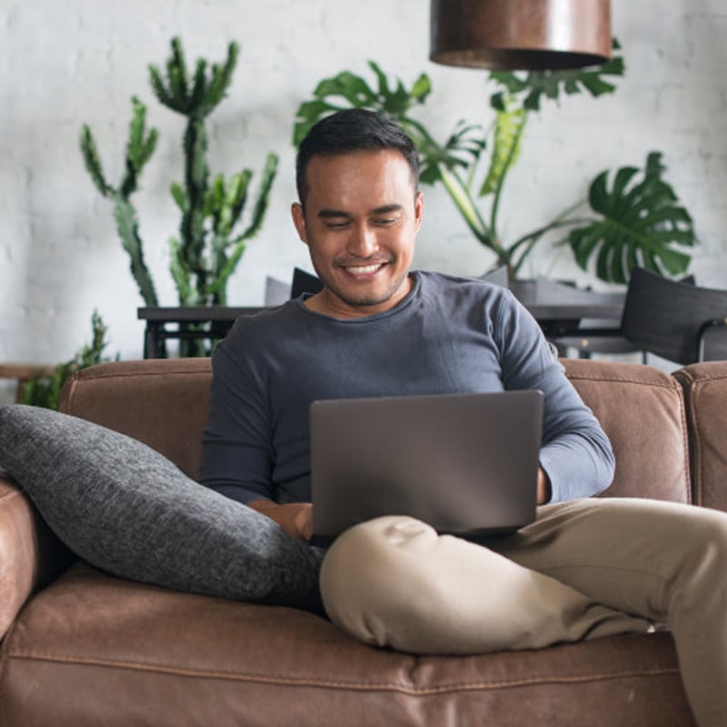 A man is using a laptop on sofa