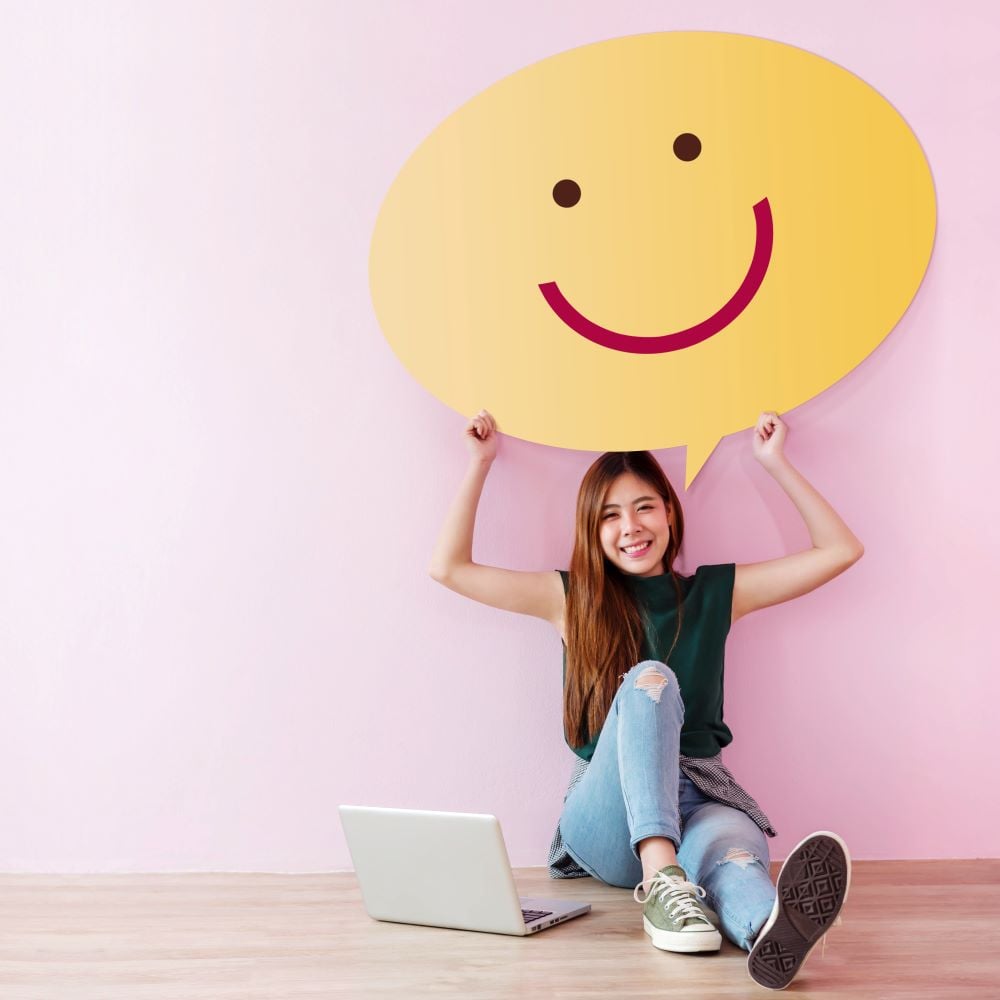 a girl is holding a happy face emoji