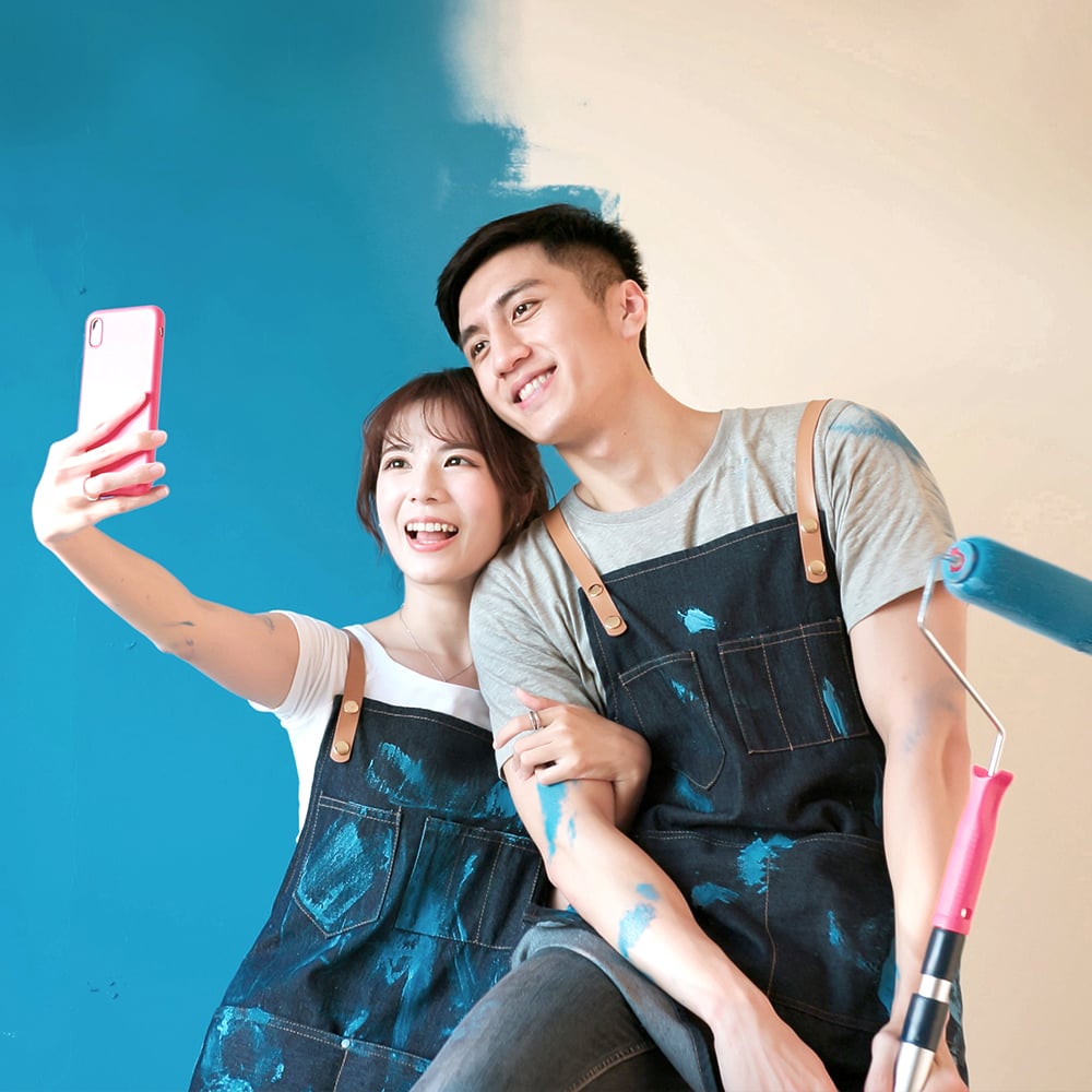 a couple is taking selfie in front of an oiled wall