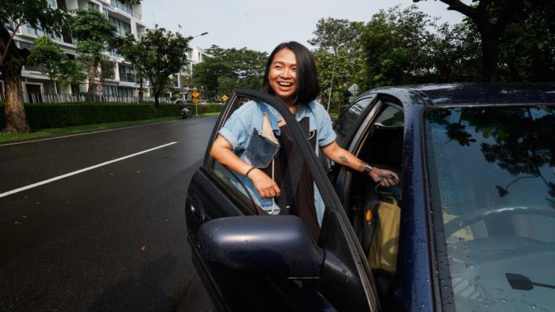 Asian woman opening a door to a black car