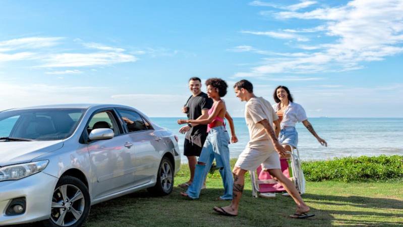 4 people walking towards a car on a lawn