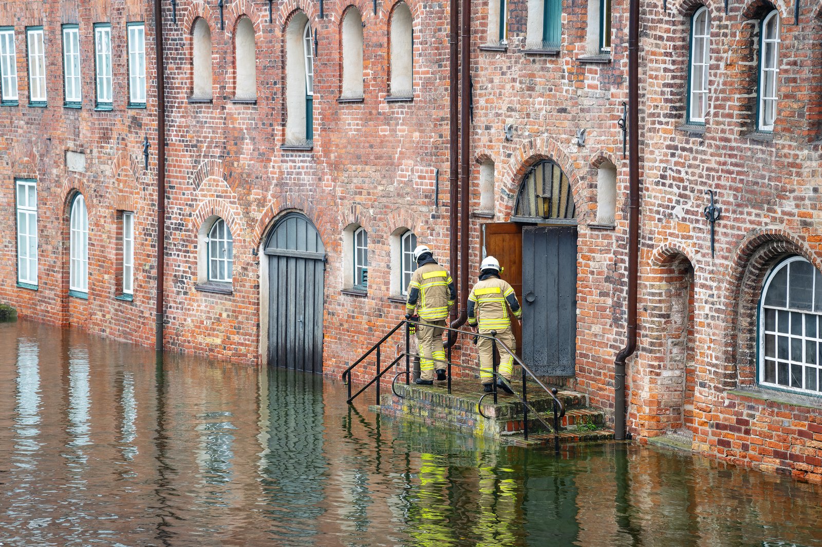 men on stairs in front of building with river