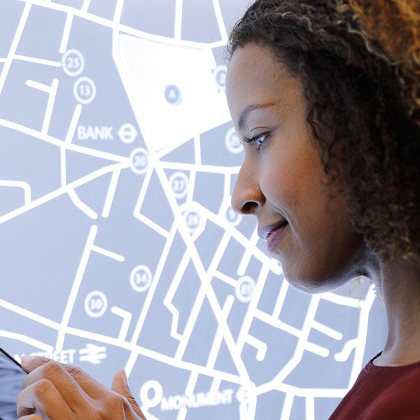 Captives-Media-Banner-Bubbles woman in front of digital map looking left
