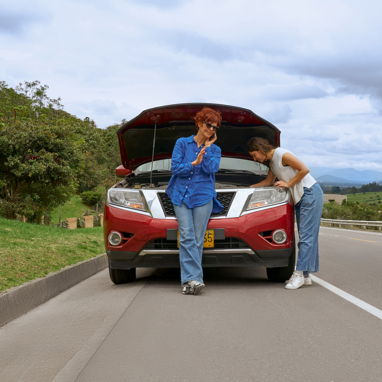 Car brokedown on a road with two women