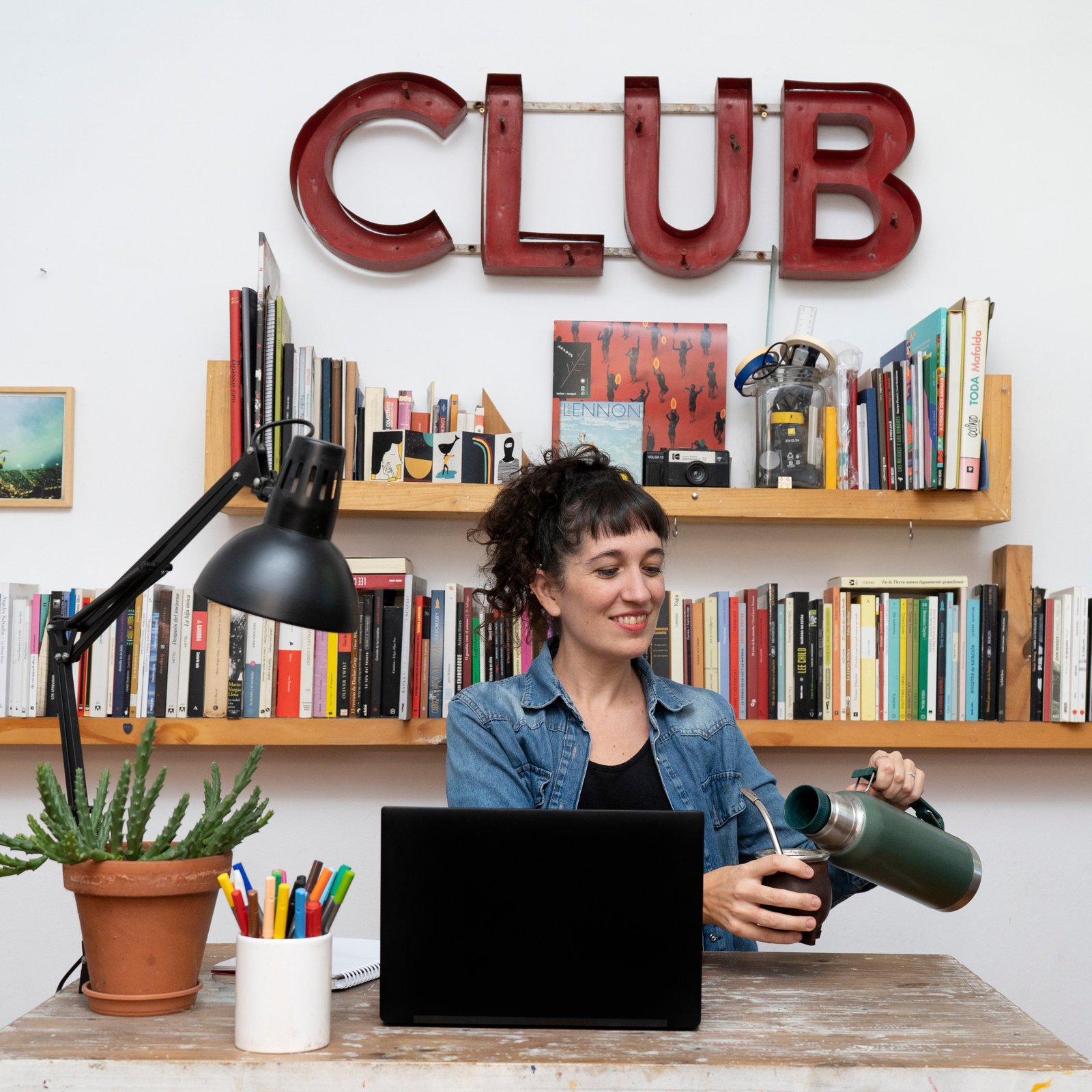 Mulher numa secretária com laptop e termo de café