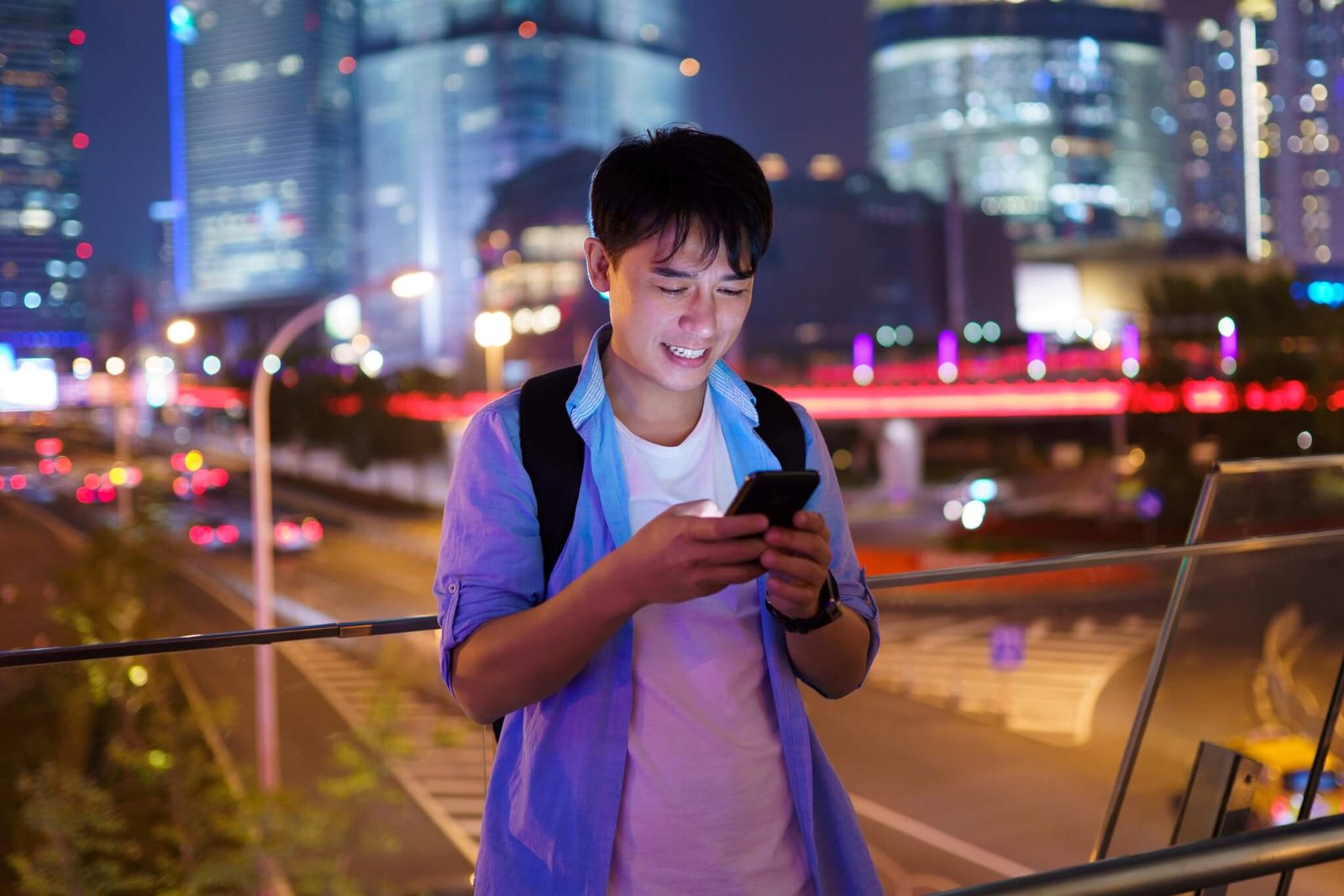 Asian man with phone in the street at night