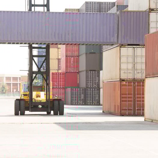 Crane moving containers at shipping yard.