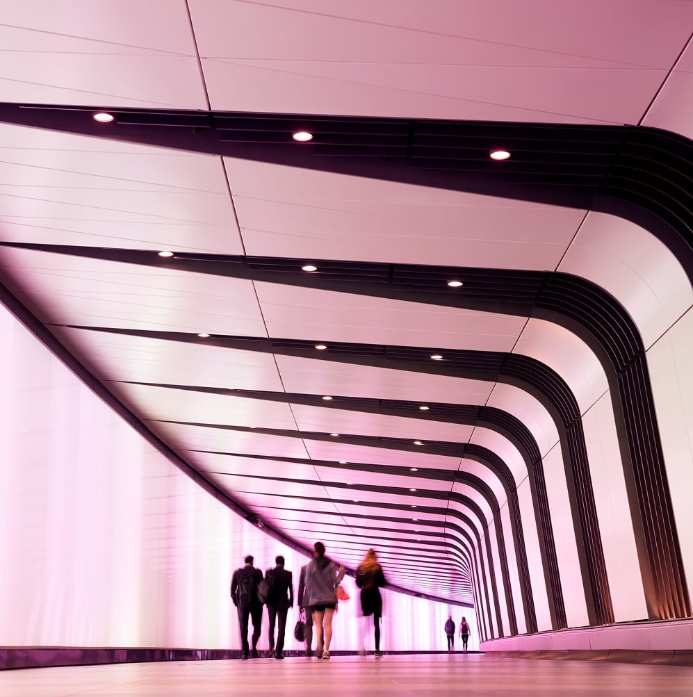 People walking through modern illuminated tunnel.