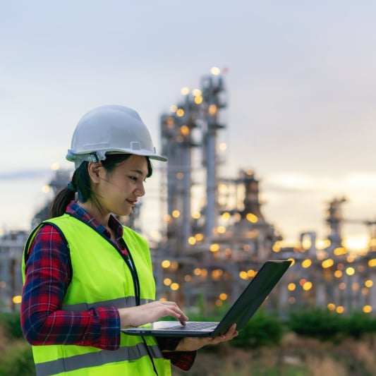 Engineer with laptop at industrial facility.