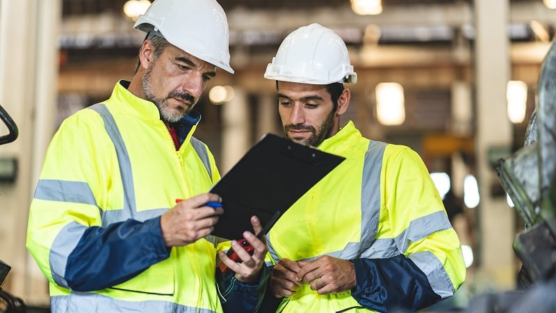 Engineers reviewing clipboard in industrial setting.
