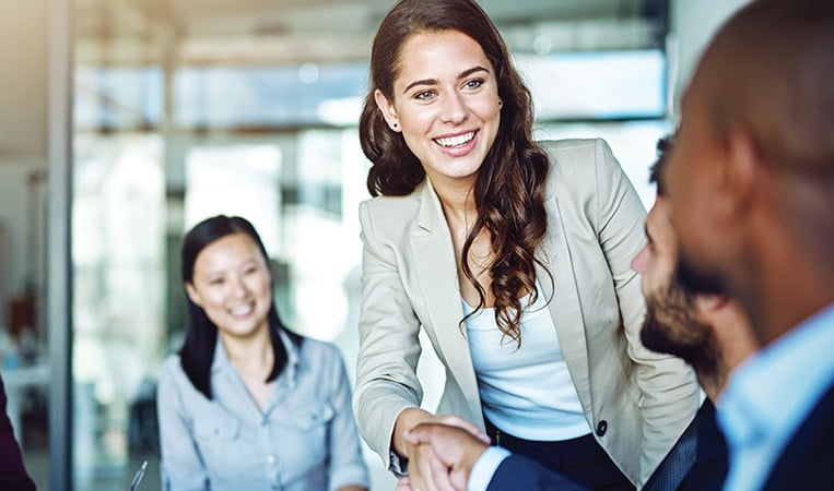 Business professionals greeting in modern office.