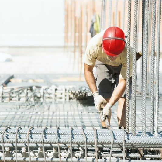 Construction worker tying steel rebar onsite.