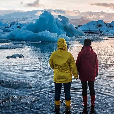 two people standing in a lake in front of mountains