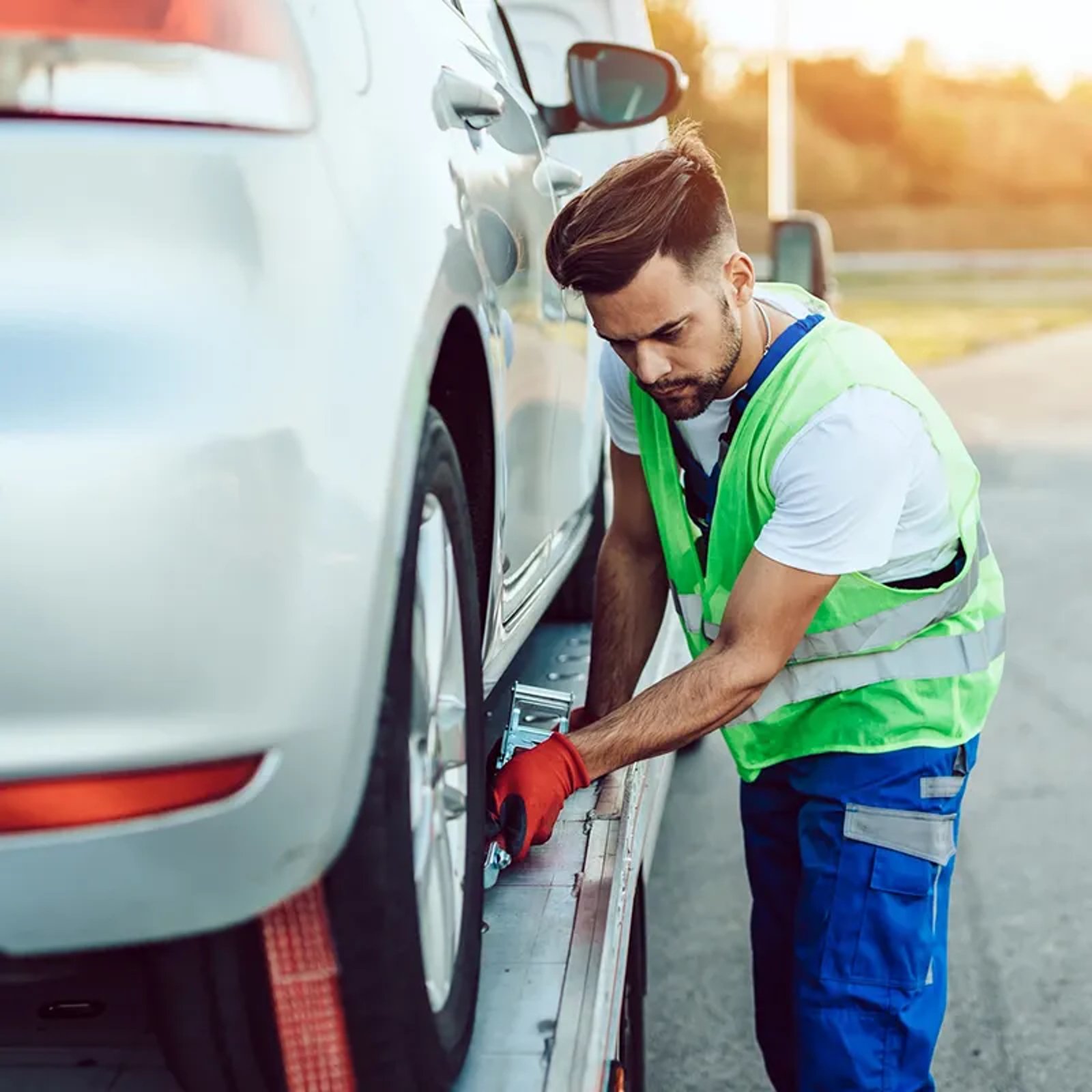 A worker secures a car on a forklift using safety tape