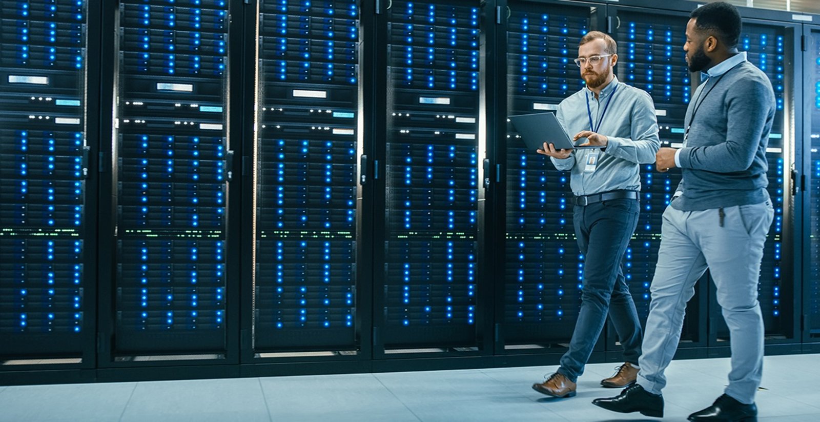 Two persons walking past mainframe in data centre