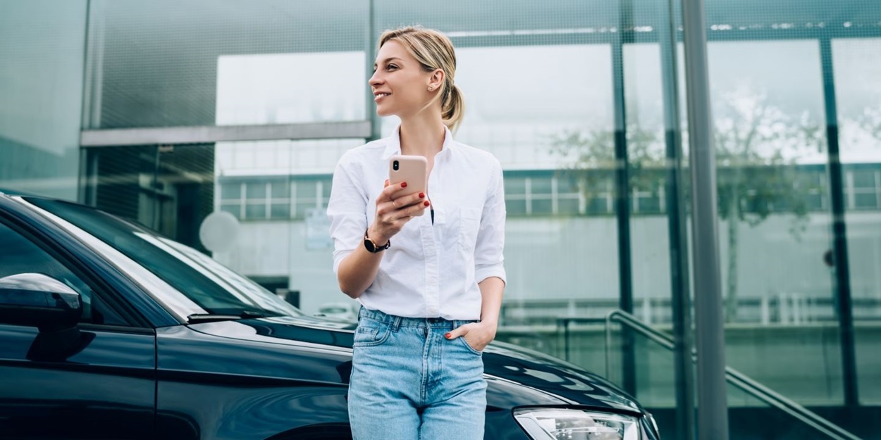 Woman with cellular standing near automobile