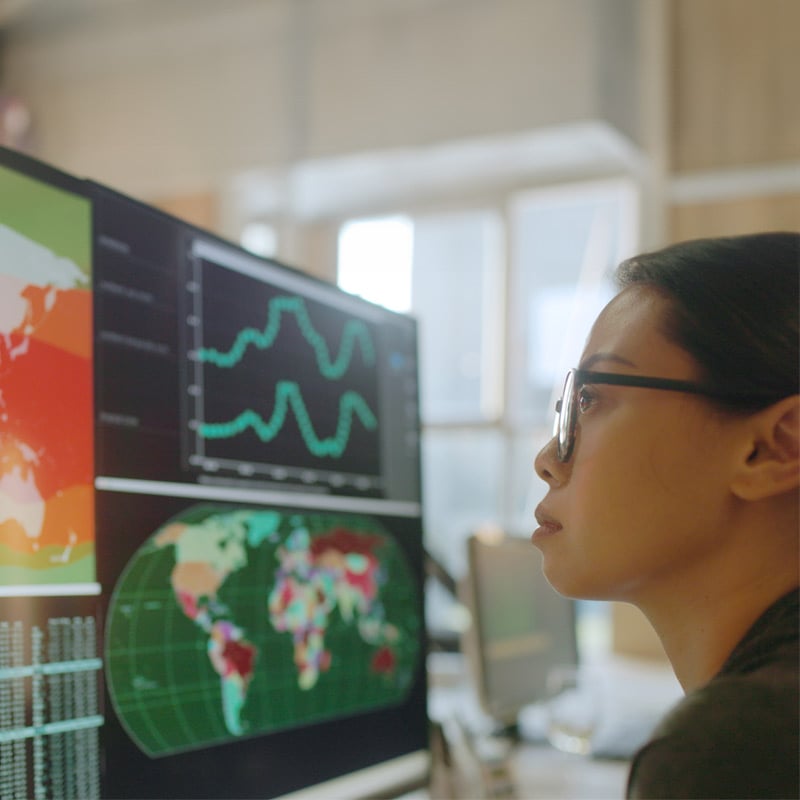 Young asian woman looking at world data and metrics on screen