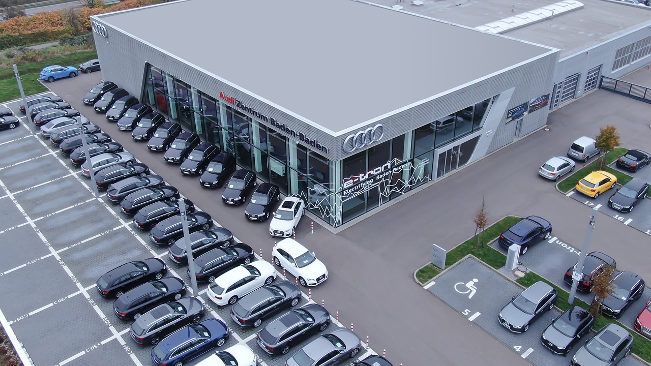 Autohaus mit vielen davor geparkten Neuwagen. 